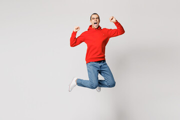 Full body young excited overjoyed middle eastern man wear red hoody casual clothes jump high do winner gesture clench fist isolated on plain solid white background studio portrait. Lifestyle concept.