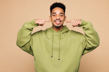 Young smiling man of African American ethnicity wears green hoodie casual clothes point index...