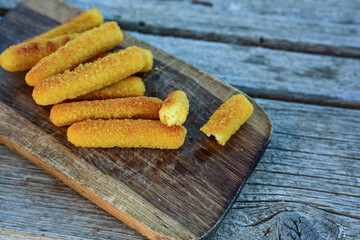 Vegetarian italian cheese breaded  oven baked  mozzarella sticks with  fresh basil on wooden background.Italian street food.