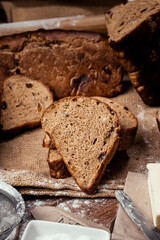rye bread with raisins, dried apricots, sunflower seeds, caraway seeds, two loaves of bread on a wooden background, flour, sieve, rolling pin, eggs, homemade bread, wheat ears, black bread with butter