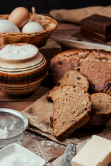 rye bread with raisins, dried apricots, sunflower seeds, caraway seeds, two loaves of bread on a wooden background, flour, sieve, rolling pin, eggs, homemade bread, wheat ears, black bread with butter