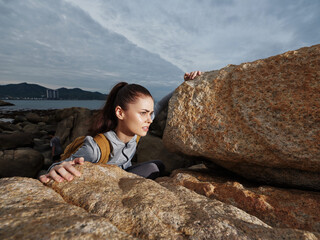 Determined female climber navigating rocky terrain, showcasing adventure and resilience against a...