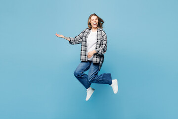 Obraz premium Full body young excited woman she wears checkered grey shirt casual clothes jump high play imaginary air guitar isolated on plain pastel light blue cyan background studio portrait. Lifestyle concept.