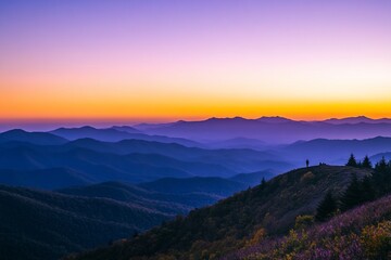 Obraz premium Vibrant sunset over layered mountain ranges, lone figure silhouetted on peak.