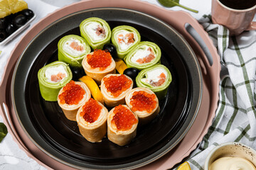 green pancakes rolls with Philadelphia cheese, red fish, red caviar, lemon, olives, pancakes with caviar, spinach, flatlay, Maslenitsa, Japanese rolls, cream cheese with salmon, still life