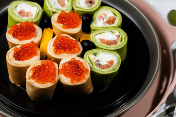 green pancakes rolls with Philadelphia cheese, red fish, red caviar, lemon, olives, pancakes with caviar, spinach, flatlay, Maslenitsa, Japanese rolls, cream cheese with salmon, still life