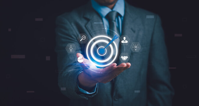 Concept of goals and objectives , businessman hand showing dartboard and arrow to define business target , business plan , marketing , strategy or organization mission