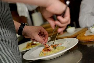 the chef decorates the dish before serving it in the restaurant kitchen