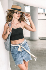 Happy woman with straw hat and backpack enjoying summer walks. A young tourist walking on the streets of Europe.
