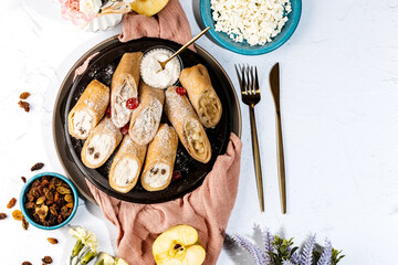 sweet rolls, pancakes with cottage cheese, raisins, apples, powdered sugar and dried cranberries, pancakes with sour cream, flatlay, beautiful light composition with dessert, roses, carnation flowers
