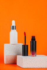 White tube and red spray on light white podiums. White blank unbranded flacons with cosmetology products. Professional concept of skin care on orange background.