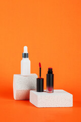 White tube and red spray on light white podiums. White blank unbranded flacons with cosmetology products. Professional concept of skin care on orange background.