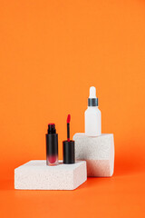 White tube and red spray on light white podiums. White blank unbranded flacons with cosmetology products. Professional concept of skin care on orange background.