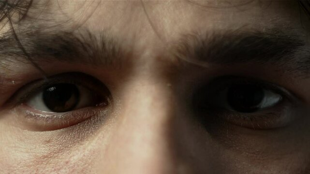 A close-up of a man's intense eyes with furrowed brows, conveying focus or determination