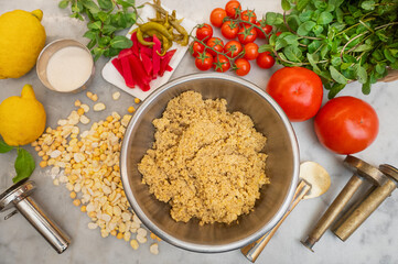 ingredients of chickpea felafel traditional food of Lebanese and Middle Eastern cuisine in a top-down view on marble table with vegetable ingredients and preparation tools