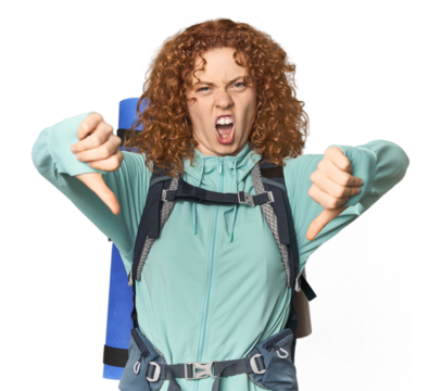 Young Caucasian redhead ready for hiking showing thumb down and expressing dislike.