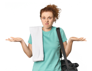 Young Caucasian redhead with gym gear doubting and shrugging shoulders in questioning gesture.