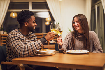Two friends are having dinner at restaurant. They are toasting with wine.