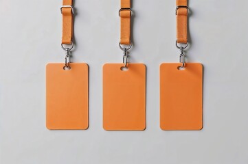 Three orange blank ID tags hanging from lanyards on a light gray background