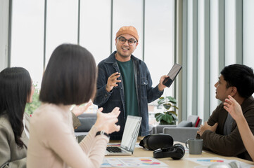 Asian male businessman explaining Happily holding a tablet in a meeting, brainstorming and talking about analysis, innovation, collaboration. online business Sales techniques and strategic planning