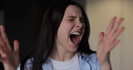 Close up of a young stressed woman shouting on living room background. Motions concept. Woman's reaction to bad news.