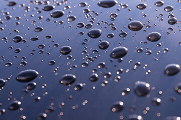 Close-up of water droplets creating an abstract texture on a glass surface with soft reflections