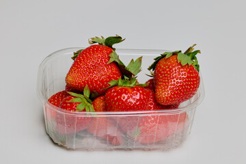 a plastic casserole with strawberries on a table