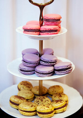 Sweet colorful macarons on a three-tiered plate on a white background closeup