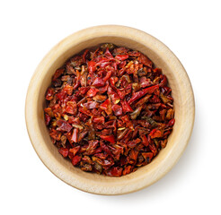 Red pepper flakes in a wooden plate on a white background. Crushed peppers view top