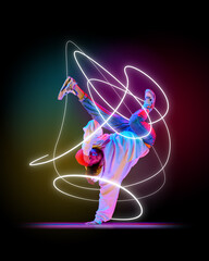 Male dancer, breakdancer balancing on one hand, with neon pink and white light swirls capturing...
