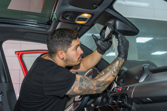 Man adjusting rearview mirror inside a car interior.