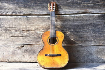 Classic acoustic guitar resting against rustic wooden backdrop in serene setting