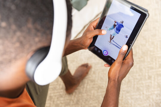 Using tablet and wearing headphones, man editing photo of beach scene