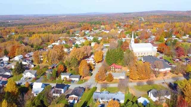 Aerial view of a neighborhood at sunshine with a church and autumn, fall colored trees, suburban village, calm and quiet, grey sky, copy space