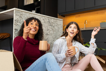 Sitting on floor with mugs, lesbian couple enjoying conversation at home