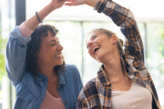 Two women dancing together, smiling and enjoying their time at home