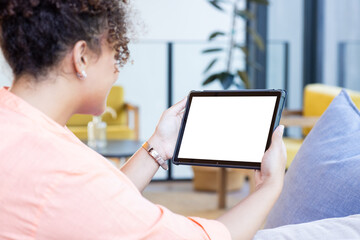 Holding tablet, woman with curly hair browsing in modern living room, copy space, at home