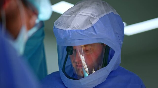 Portrait of a calm confident male doctor in protective helmet. Doctor working at surgery on trauma.