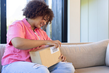 Opening package, woman sitting on couch and smiling in casual clothes, copy space, at home