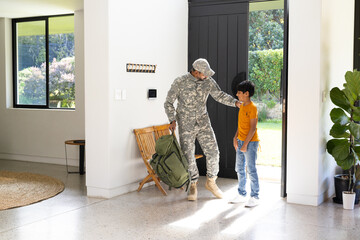 Military indian father in uniform greeting young son at home entrance, bonding moment