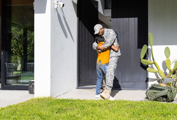 Hugging young son, military indian father in uniform reuniting at home entrance, copy space