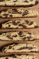 Overhead view of chocolate chip biscotti on a chopping board, top view of chocolate chip cantucci cookies on a brown board, flatlay of slices of biscotti cookies or twice baked cookies
