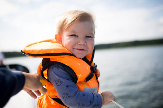 Małe dziecko pływa bezpiecznie z rodzicami na jachcie w kamizelce asekuracyjnej. Bezpieczeństwo na wakacjach 