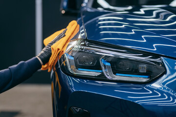 Wiping the blue car body with fiber after polishing