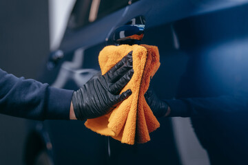 Wiping the blue car body with fiber after polishing