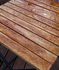 The wooden table is wet with raindrops