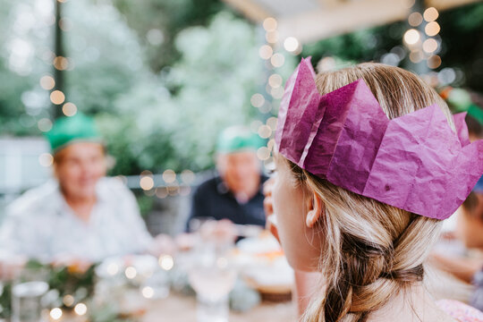 Young teenage girl wearing a paper crown with grandparents on the backdrop.