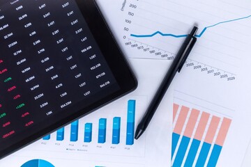 Stock market financial data analysis concept. Investment financial data on digital screen and business data graphs on paper printouts.