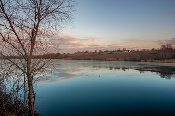 Beautiful sunrise on the pond , pond near the village .Red and orange sunrise in the sky , trees and houses , landscape on the lake with sunrise , reflactions on water 