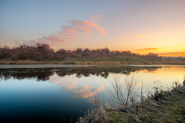 Beautiful sunrise on the pond , pond near the village .Red and orange sunrise in the sky , trees and houses , landscape on the lake with sunrise , reflactions on water 